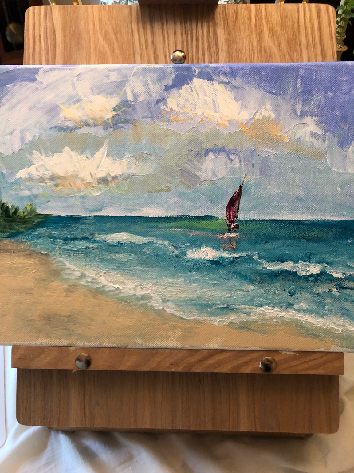 Mary's coastal painting of a sailboat beyond rolling turquoise waves